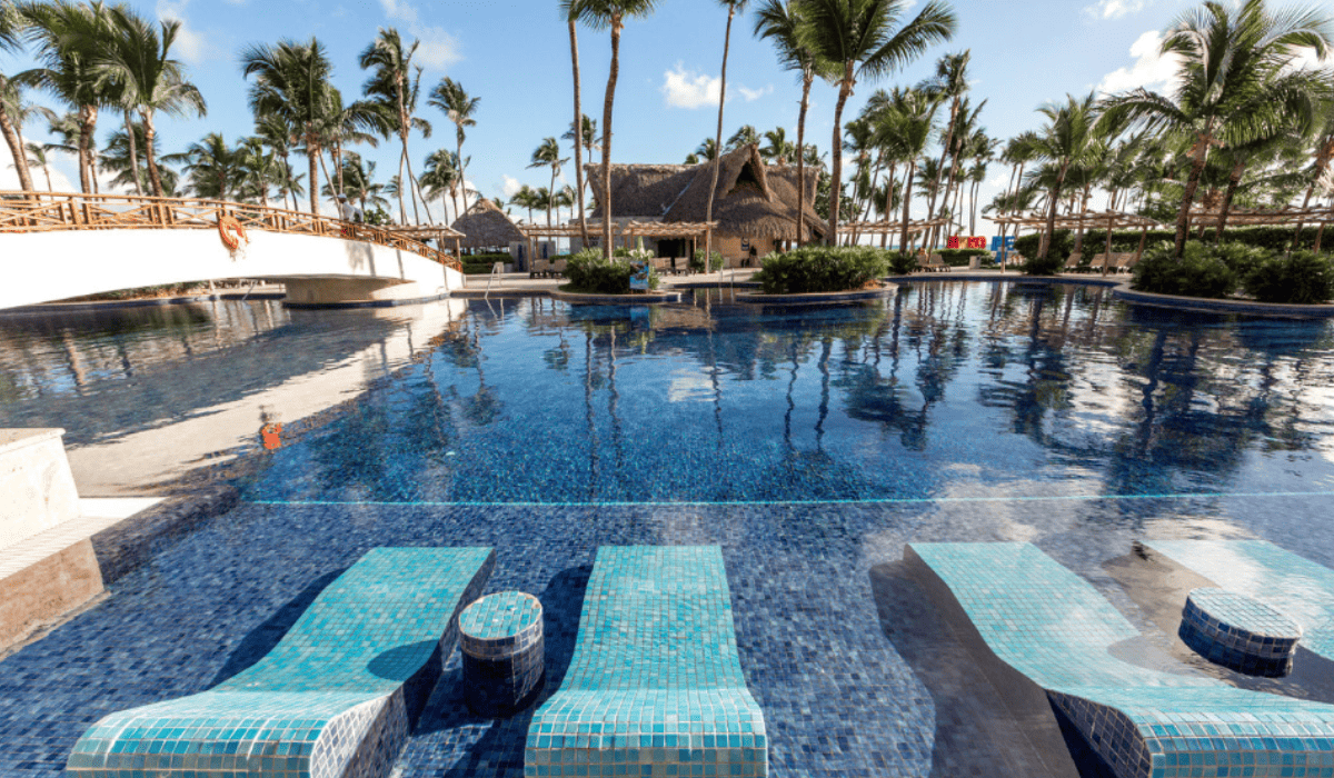 pool with a bridge and a coconut trees nearby inside the Barcelo Bavaro Palace Punta Cana