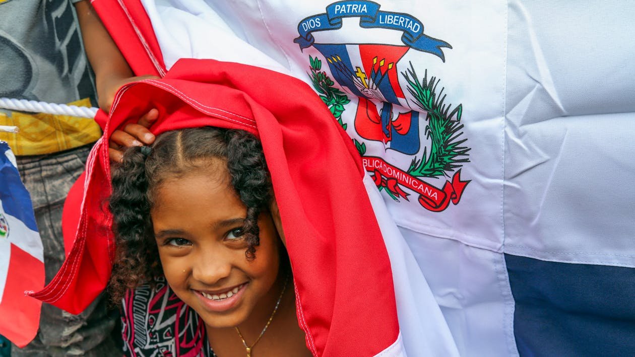 Girl smiling underneath the Dominican Republic flag.