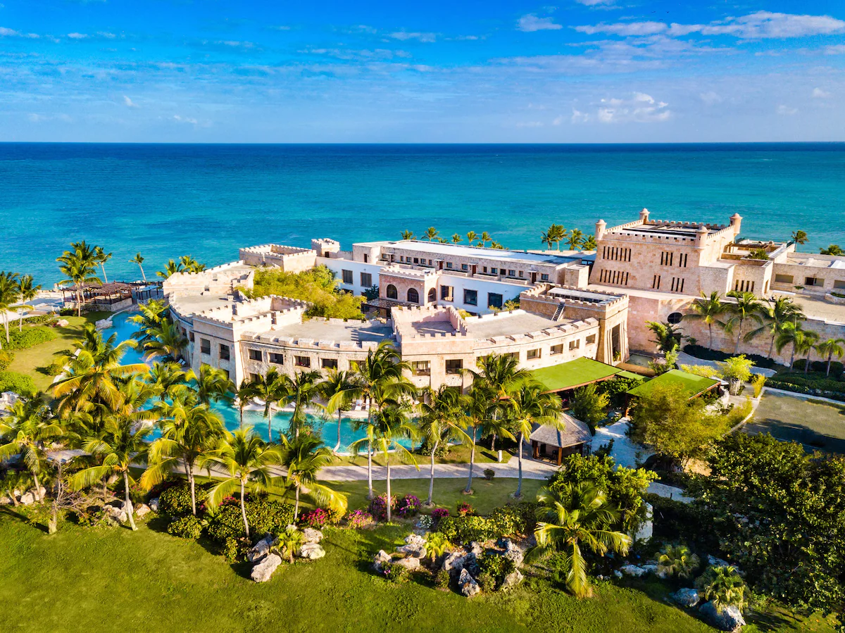 A breathtaking aerial view of Sanctuary Cap Cana, a luxury resort resembling a castle by the ocean, perfect for a romantic Punta Cana honeymoon.